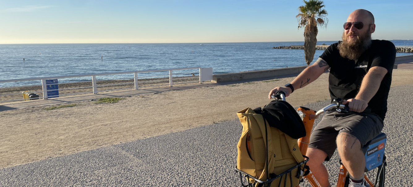 Joris on a bike in Barcelona with the beach on a bacgkround